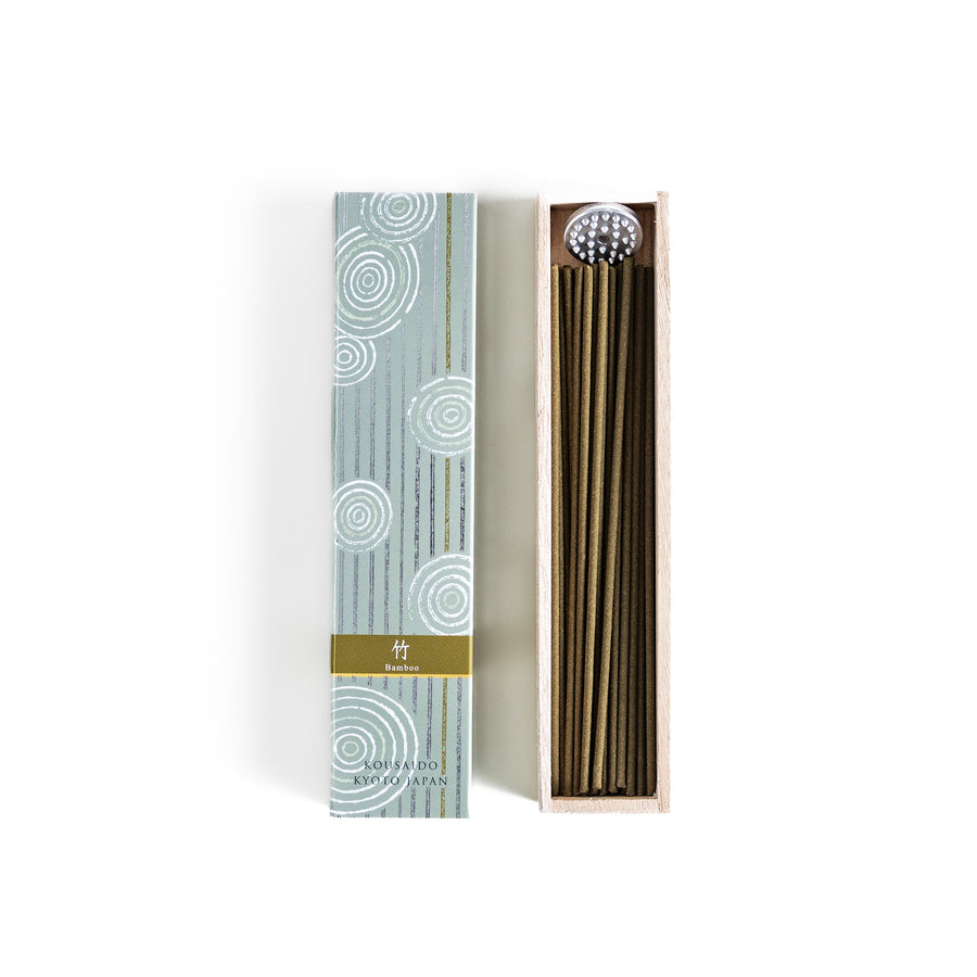 Incense in a light wooden box with earthy green sticks, featuring an elegant soft green package adorned with white circular patterns for a serene aesthetic.