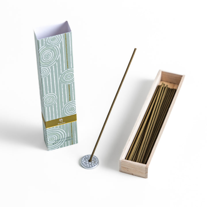 Incense in a light wooden box with earthy green sticks, featuring an elegant soft green package adorned with white circular patterns for a serene aesthetic.