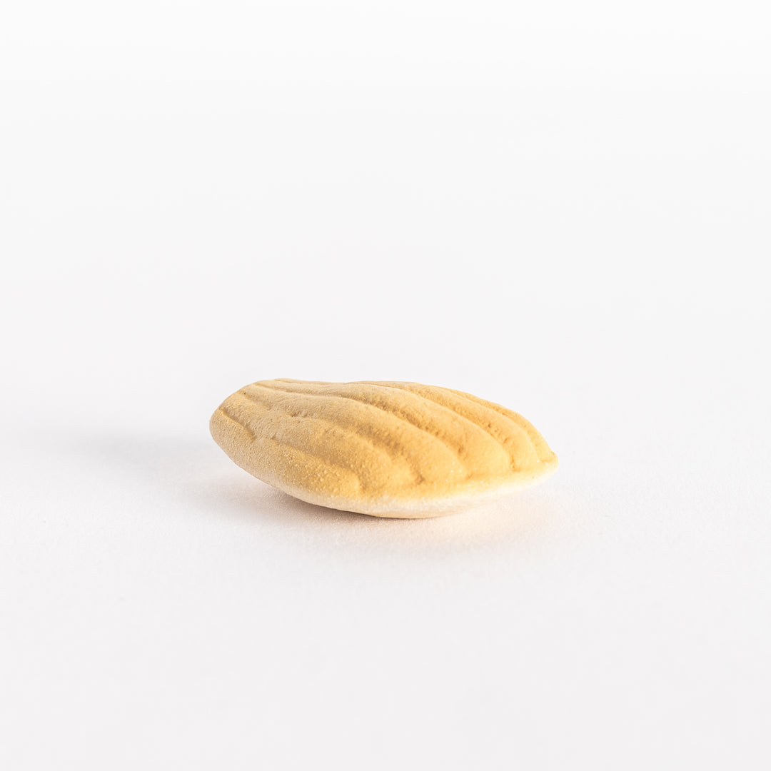 A side view of the ceramic golden madeleine chopstick rest, featuring its scalloped texture and smooth curves.