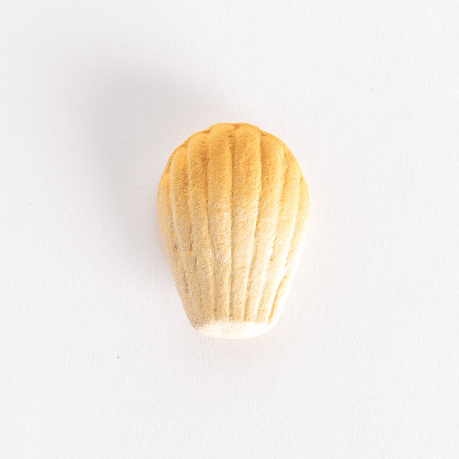 A ceramic chopstick rest shaped like a golden madeleine, showcasing its textured ridges on a white background.