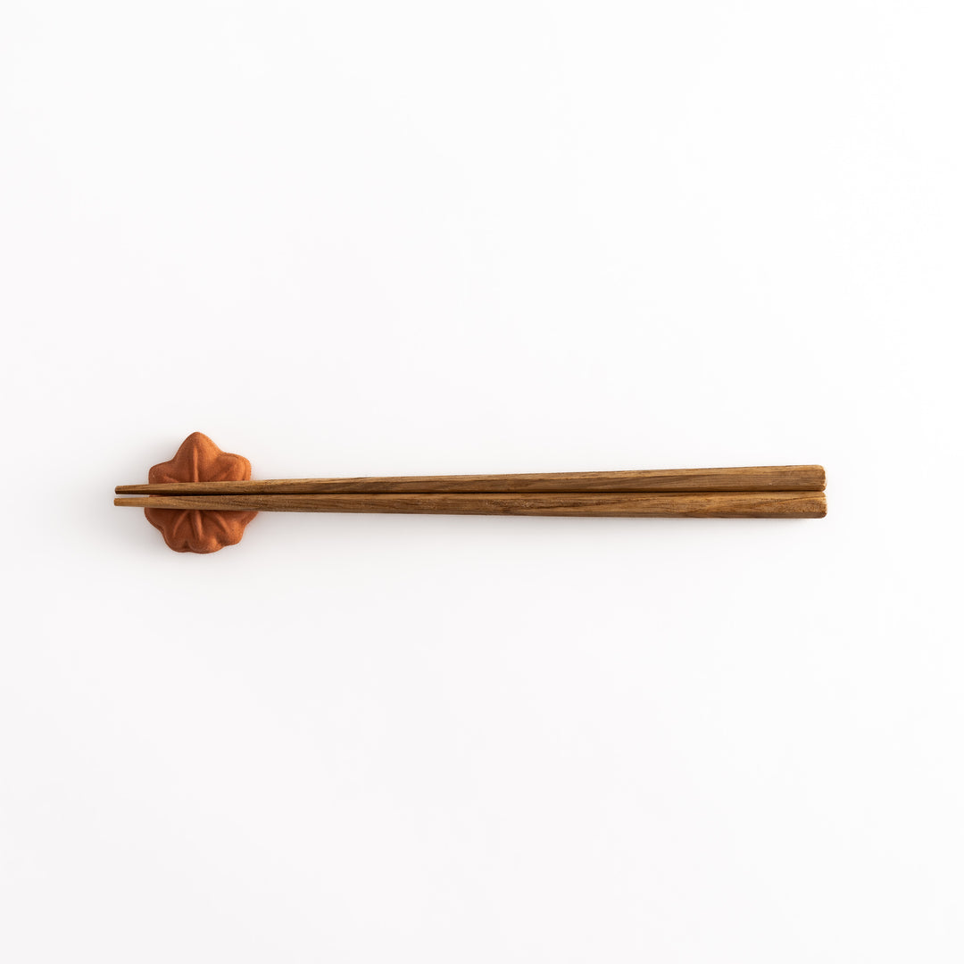 Distant view of chopsticks resting on the maple leaf bun chopsticks rest, highlighting its charming design and warm golden-brown color.