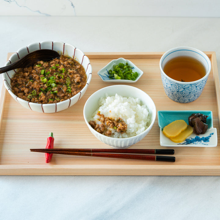 Top view of a mapo tofu dish with minced pork and green onions, served with steamed rice, green tea, and pickled vegetables on the side.