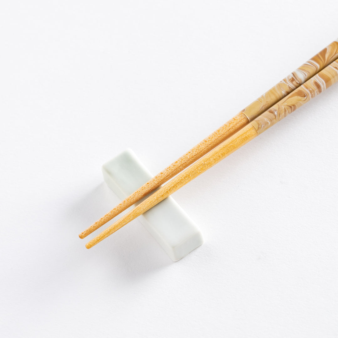 Close-up of the chopstick tips on a sleek white holder, showing the light wooden finish and clean lines.