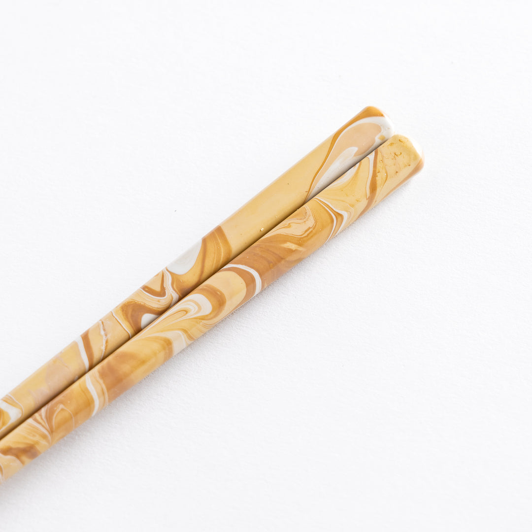 Full-length view of caramel-patterned chopsticks against a white background, showing the tapered wooden tips.