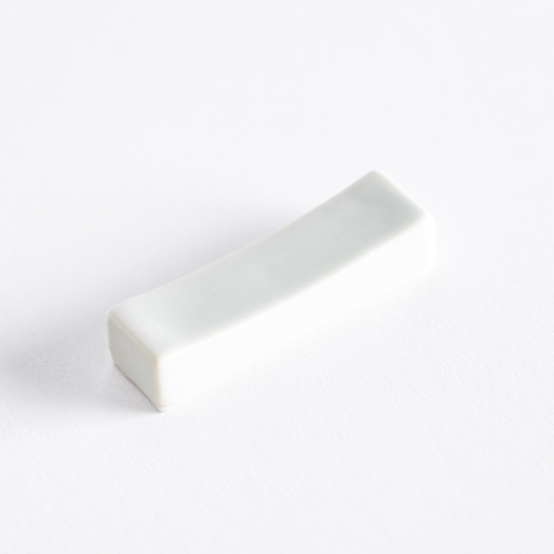 Minimalist white porcelain chopstick holder displayed alone on a clean white surface.