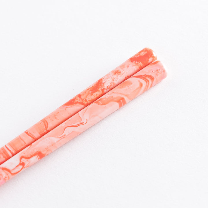 Rose Petal Fusion Chopsticks rest with their soft pink marbled design, gently placed on a pink holder, showcasing the contrast of bamboo tips.