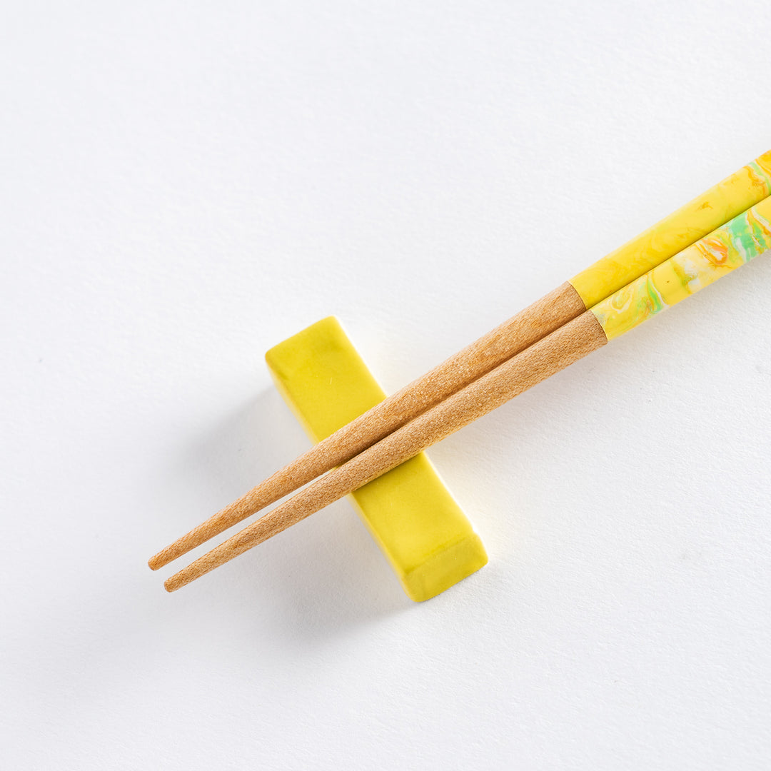 The intricate marbled design of the chopsticks in yellow, green, and orange, with a natural wooden base for a perfect balance.