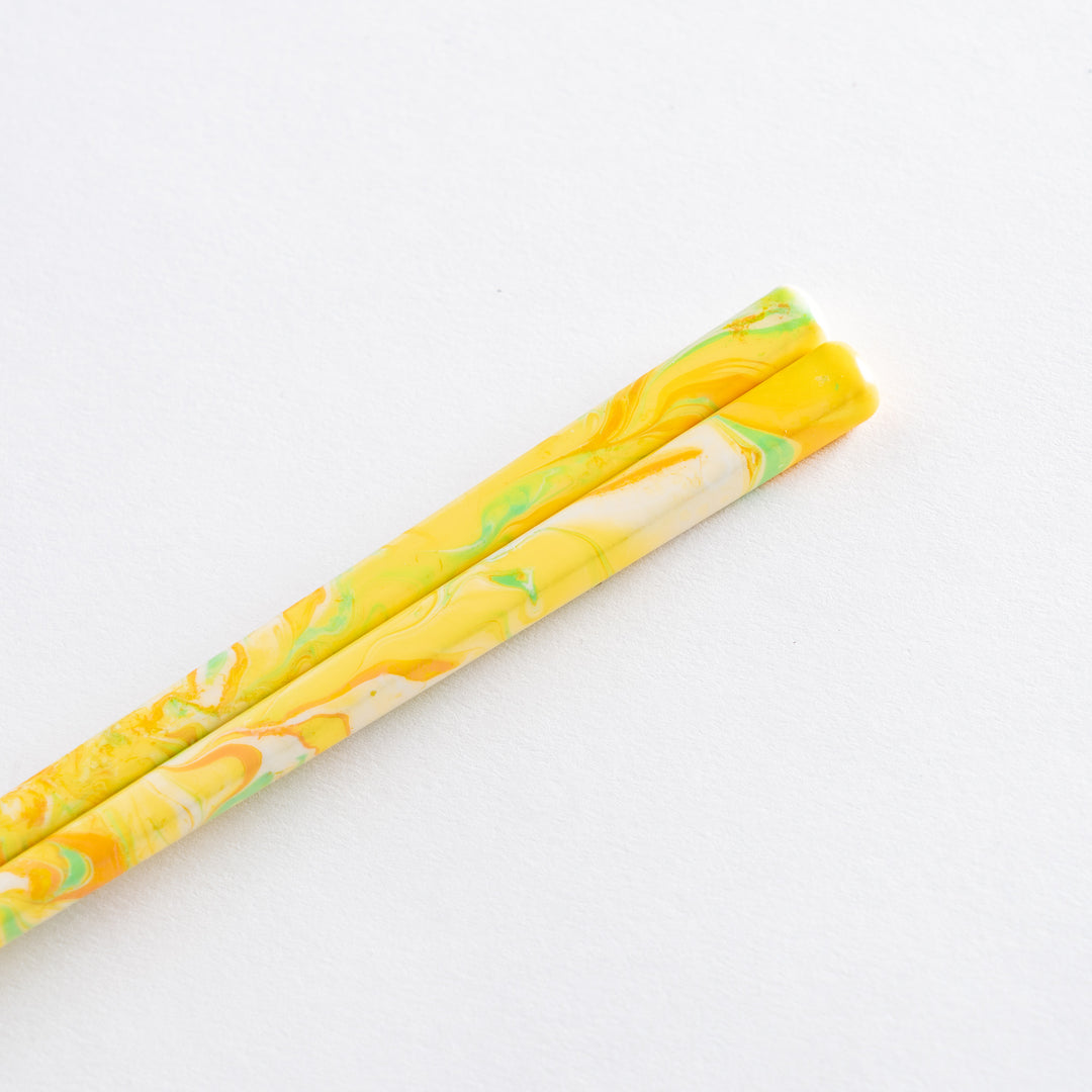 Close-up view of vibrant, marbled yellow and green tips of chopsticks, ideal for those seeking a bright and modern touch to their tableware.