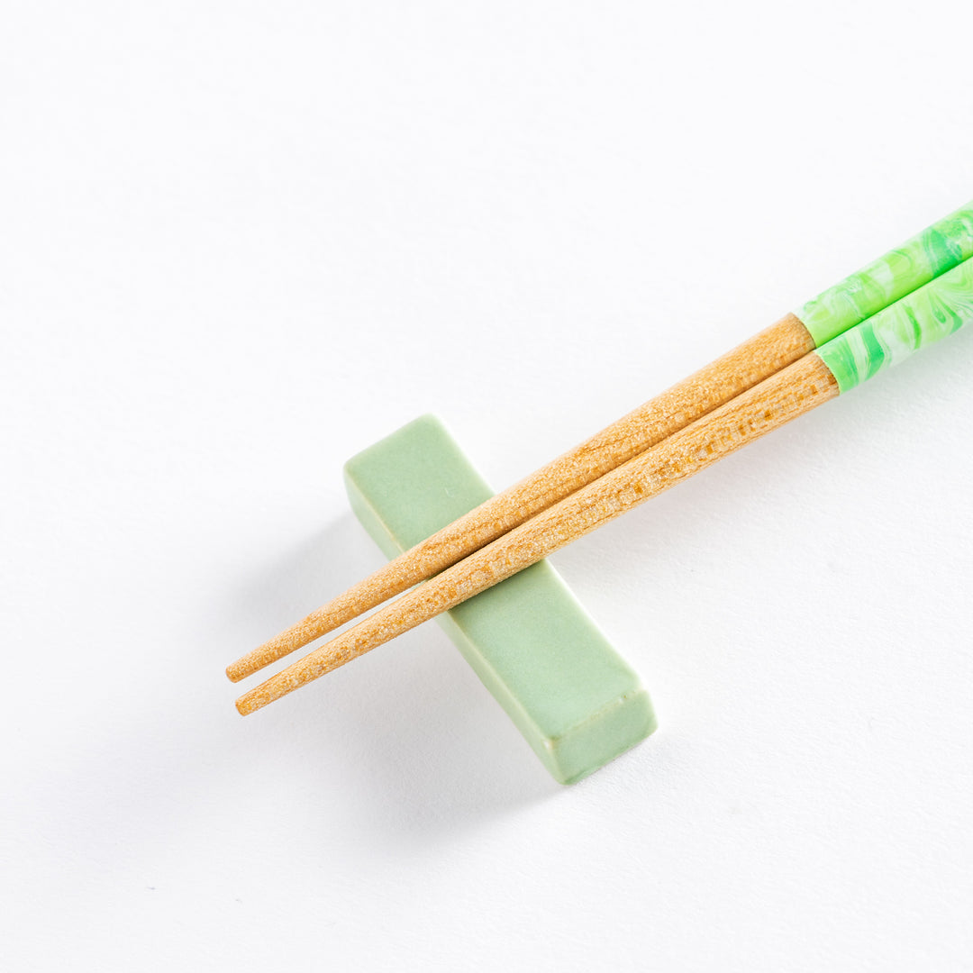 Close-up view of mint green and white marble chopsticks with a natural wood base, perfect for stylish and functional use.