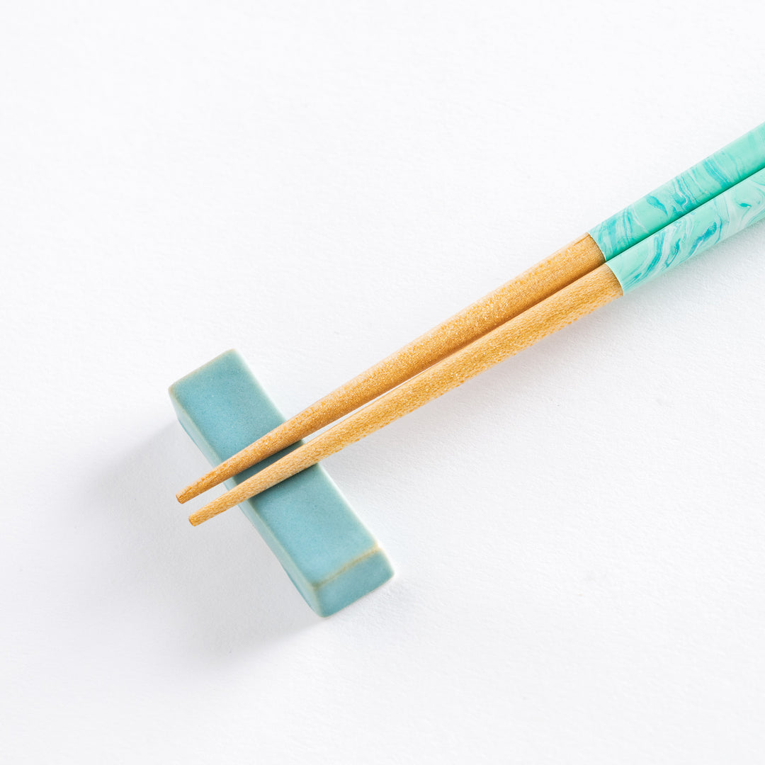 Close-up of the aqua chopsticks, highlighting the unique marbled pattern on the handles with wooden tips.