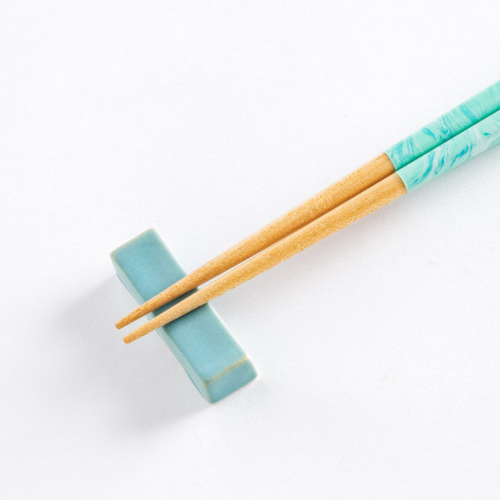 Close-up of the aqua chopsticks, highlighting the unique marbled pattern on the handles with wooden tips.