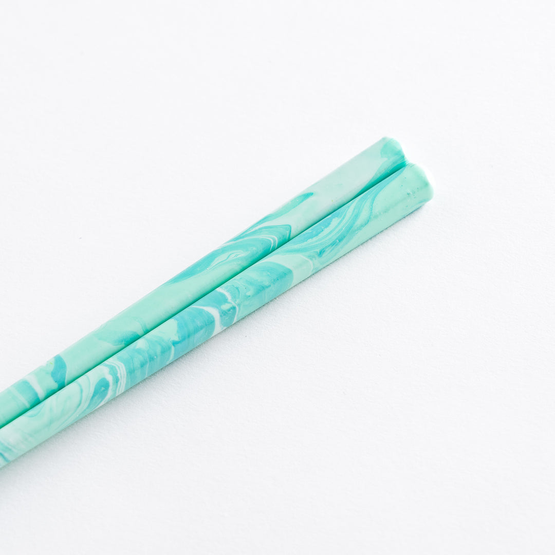 Elegant aqua chopsticks positioned against a minimalistic background, showcasing the beautiful marbling and style.