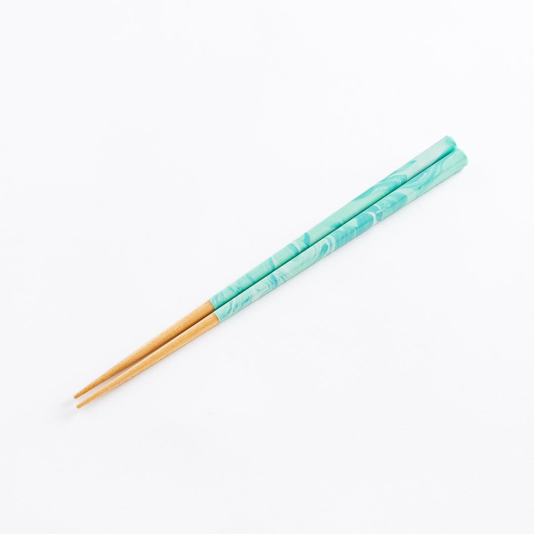 Detailed view of the aqua chopsticks with a marbled finish resting on a white background, emphasizing their design.