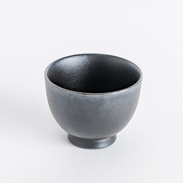 Matte black teacup displaying a refined silhouette with a subtly flared rim and sturdy base.