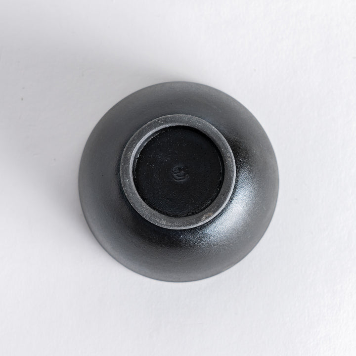 Bottom view of the matte black teacup, highlighting its sturdy base and craftsmanship details.