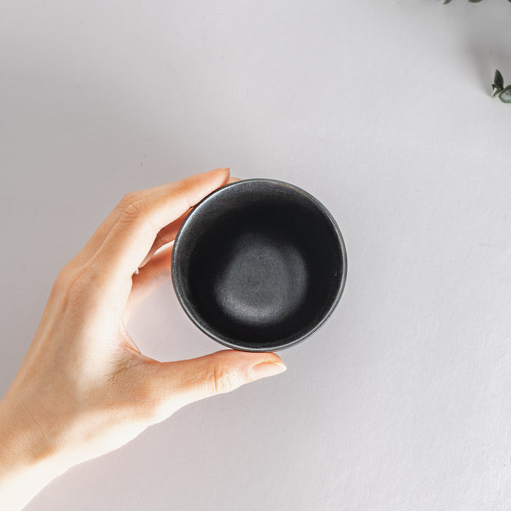 Top view of the teacup held in a hand, showcasing its sleek design and size for context.