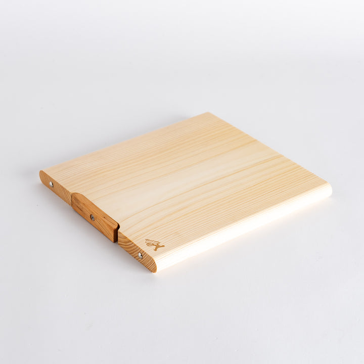 Side view of a hinoki cutting board highlighting the thickness and smooth finish, demonstrating the craftsmanship with a wooden accent for stability.