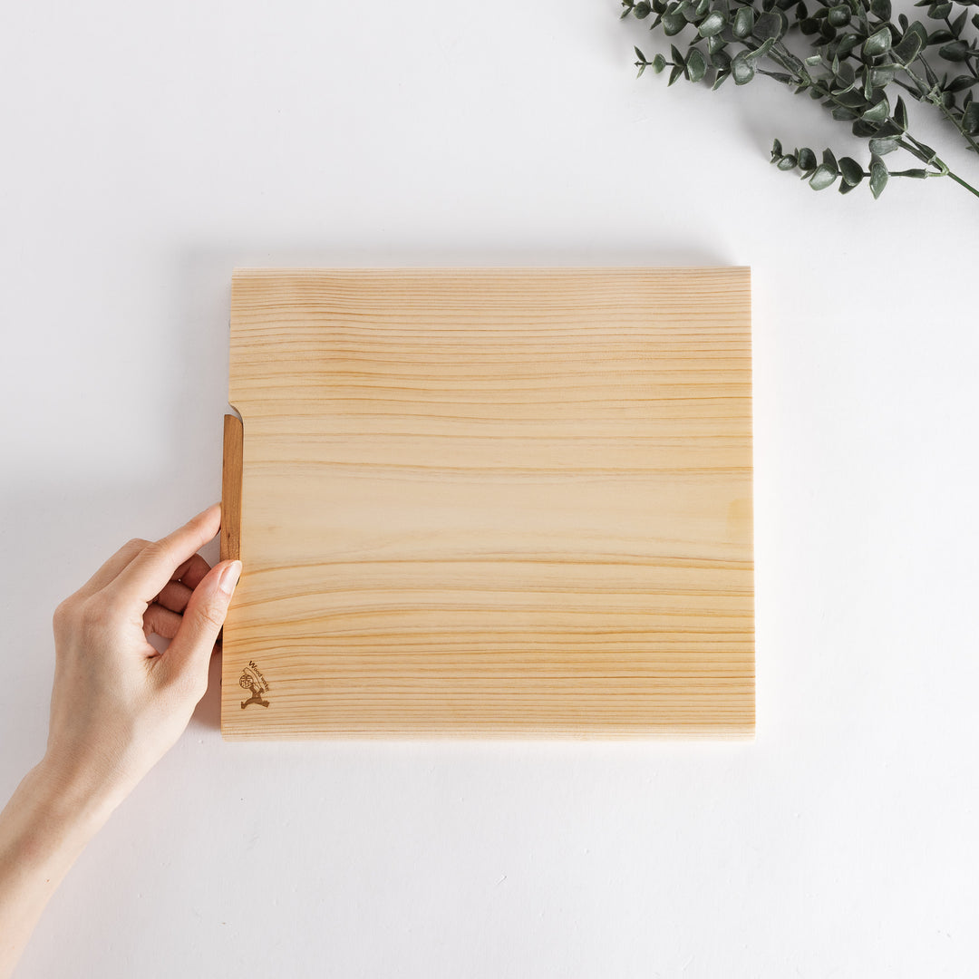 A hand holds the medium cutting board, showcasing its clean, minimalist design and the beautiful texture of the wood.