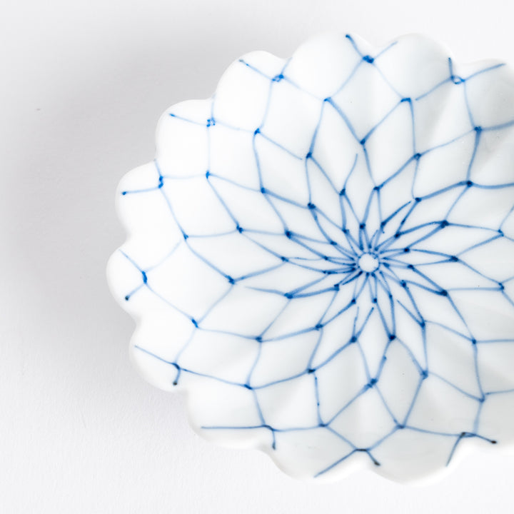 White sauce dish with a blue chrysanthemum mesh pattern and scalloped edges.