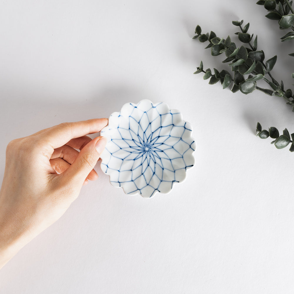 White sauce dish with a blue chrysanthemum mesh pattern and scalloped edges.