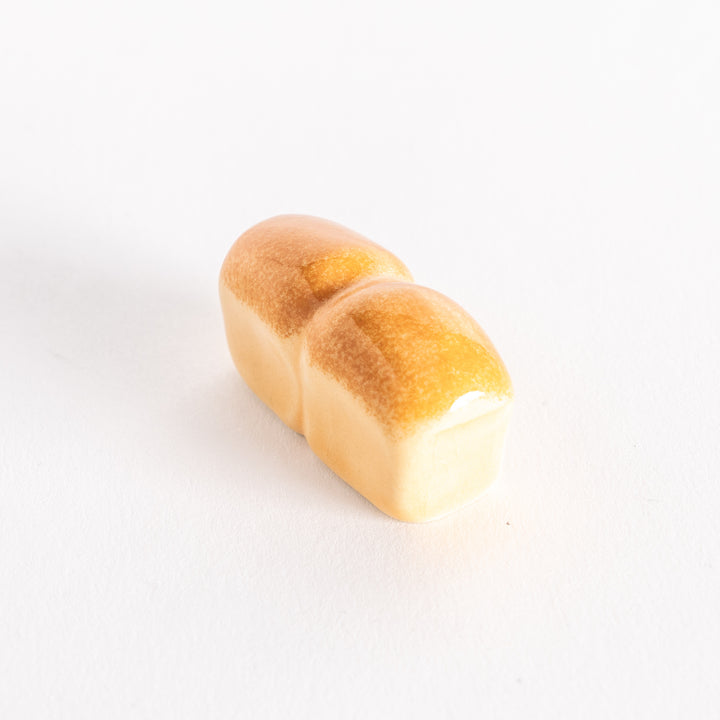 The milk bread chopsticks rest photographed from a slight angle, showing its rounded shape and glossy finish.