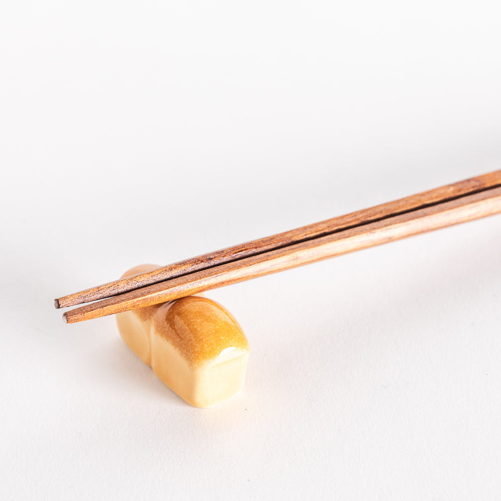 A close-up of the milk bread-shaped chopsticks rest with chopsticks resting across it.