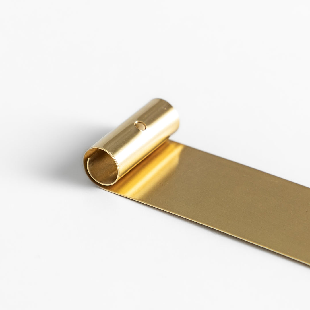 Minimalist brass incense holder with a sleek rolled-edge design, securely holding a single incense stick while the flat base catches falling ash.