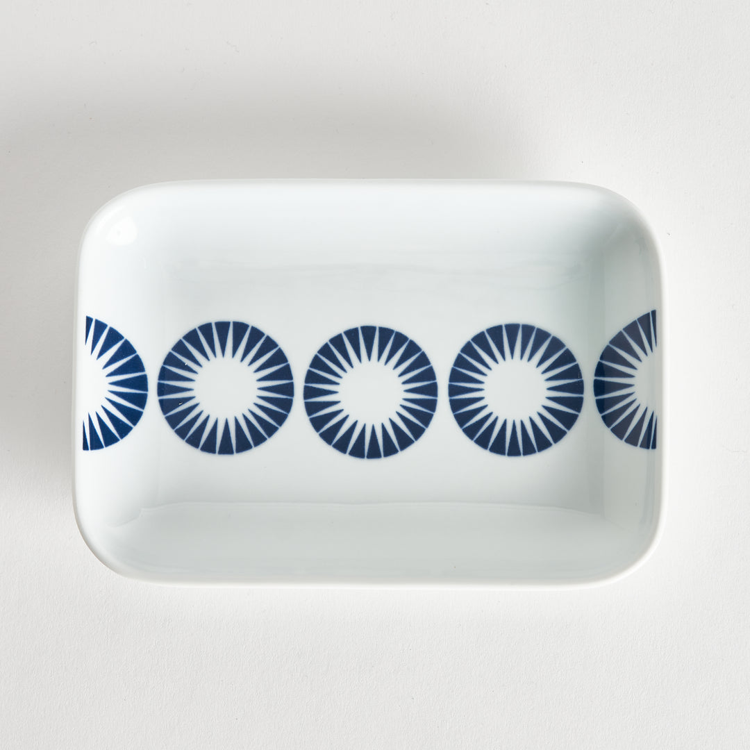 Top view of a rectangular dessert plate with a pattern of alternating blue starburst circles.