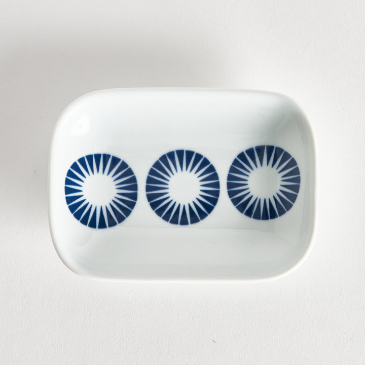 Top view of the sauce dish with three navy blue circles featuring radiating lines, placed neatly on a white surface.