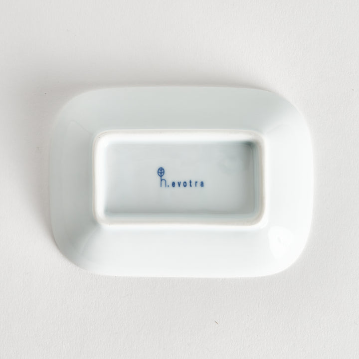 Bottom view of the sauce dish showing the smooth surface with a kiln mark, including the maker's name in the center.