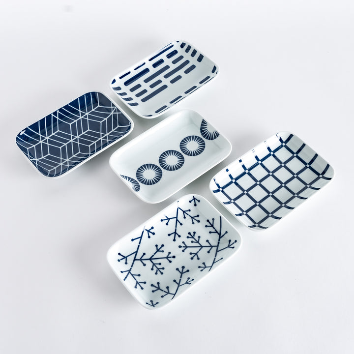 Five different dessert plates with unique indigo patterns, including geometric shapes, lines, and circular designs, on a white background.