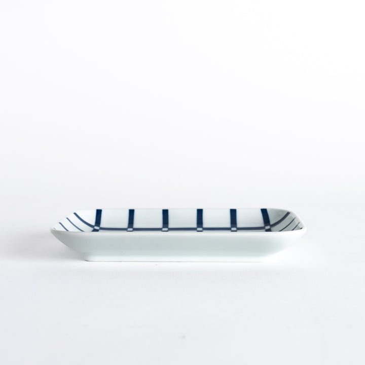 A side view of the rectangular dessert plate, showcasing the indigo lattice design and the plate's slight curvature.