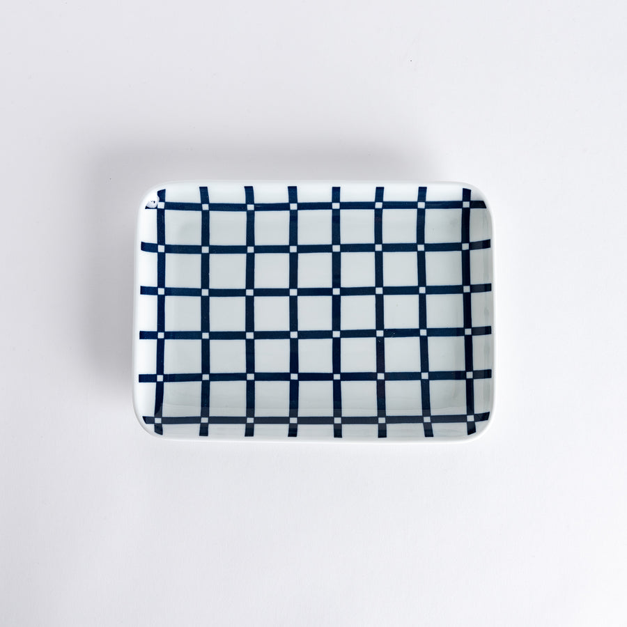 Top-down view of a dinner plate featuring a modern navy blue lattice grid pattern, with squares and lines arranged neatly on a white surface.