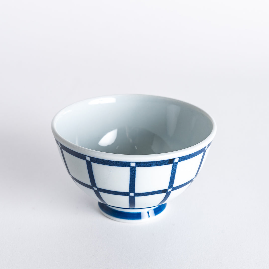 Slightly angled view of the Modern Indigo Lattice Rice Bowl, featuring a crisp navy blue grid pattern with a smooth white finish.