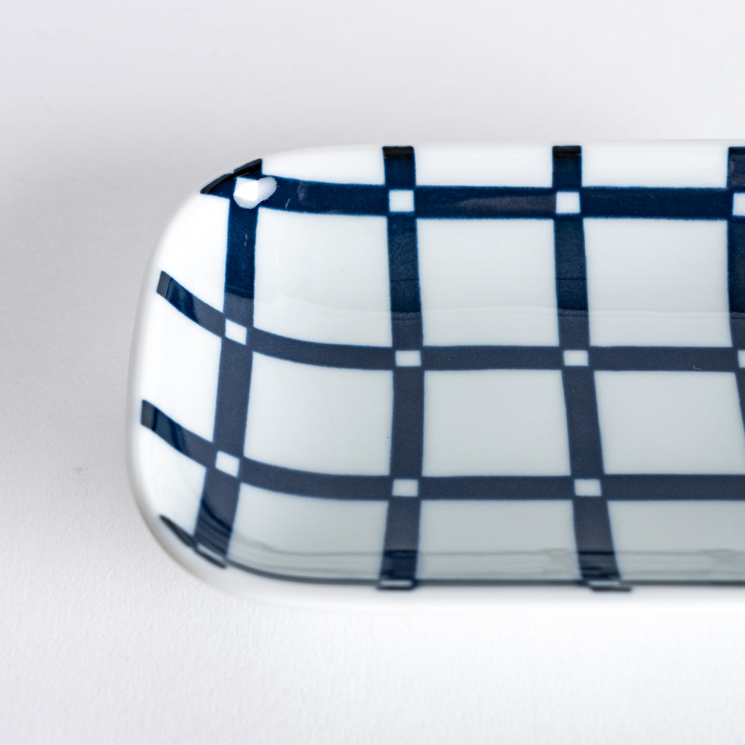 Close-up of the sauce dish with a focus on the crisp lattice pattern in navy blue and the smooth porcelain surface.