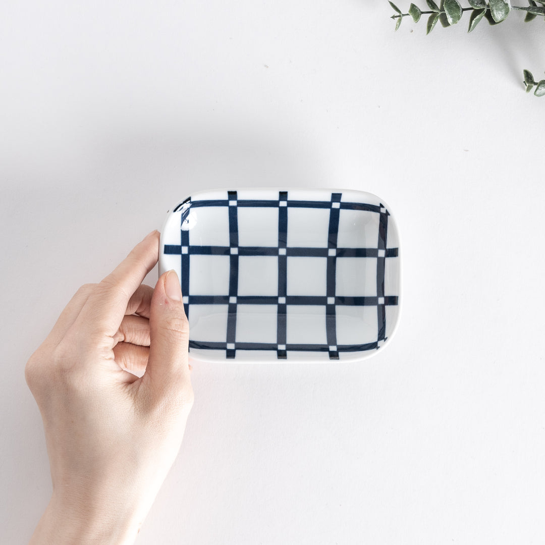 Sauce dish held in hand, captured from above, featuring a modern lattice pattern in navy blue on a white background.