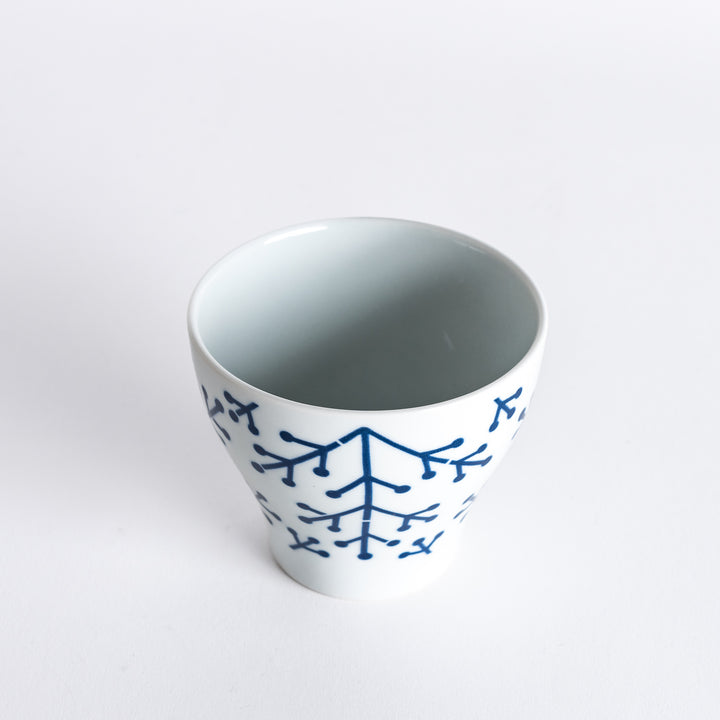 Slightly angled view of the Modern Indigo Pine Cup, highlighting the delicate navy blue pine branch pattern on the white ceramic surface.