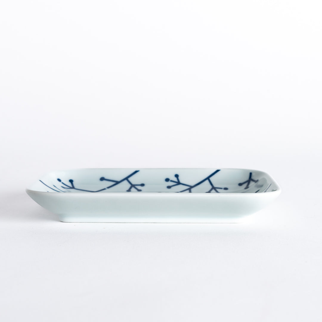 Side view of the dessert plate, emphasizing its elegant profile and the indigo pine branch design.