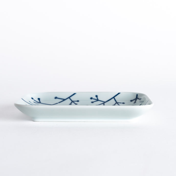 Side view of the dessert plate, emphasizing its elegant profile and the indigo pine branch design.