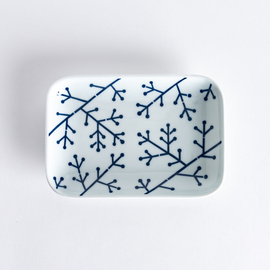 Top view of a dessert plate featuring a modern indigo pine branch pattern with intricate geometric lines and dots, set on a white background.