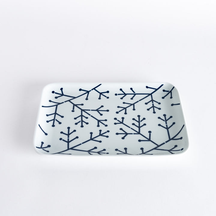 Slightly angled view of the Modern Indigo Pine Dinner Plate held in hand, highlighting the delicate navy blue pine branch pattern on a white surface.