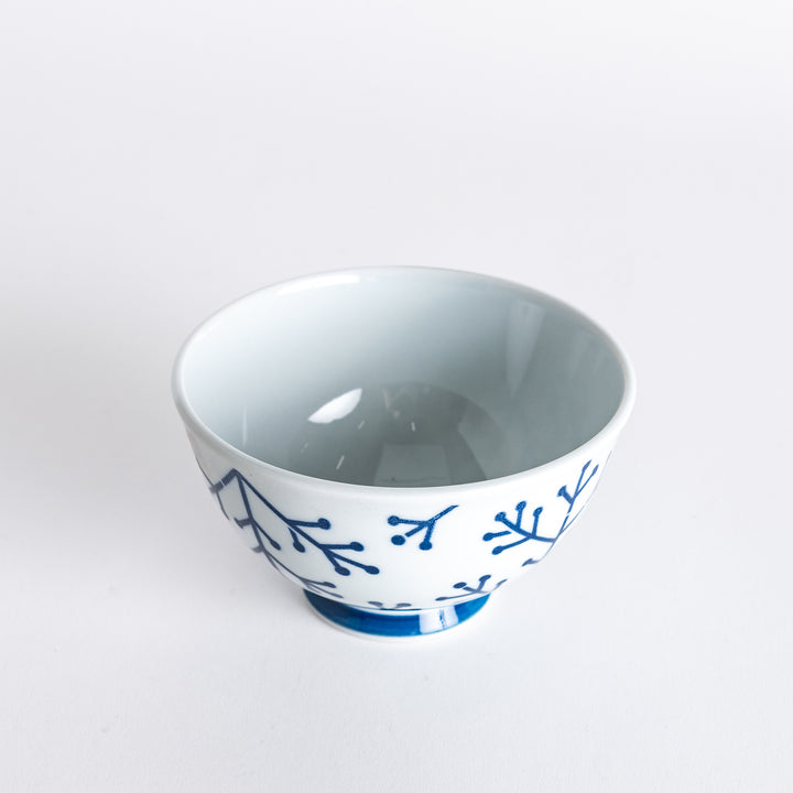 Slightly angled view of the Modern Indigo Pine Rice Bowl, highlighting the navy blue pine branch design and blue base.