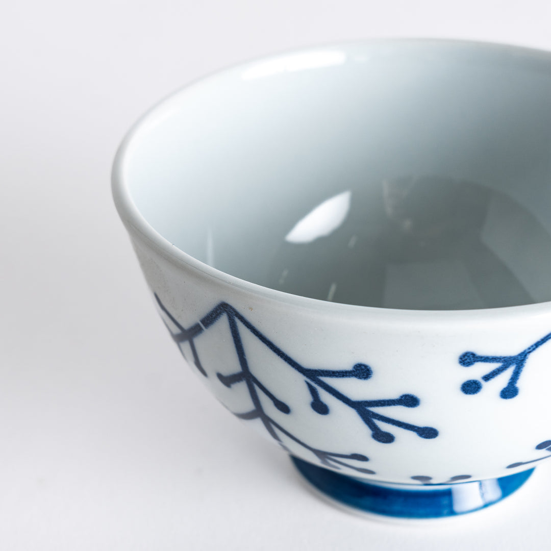 Slightly angled close-up of the Modern Indigo Pine Rice Bowl, focusing on the intricate navy blue pine branch pattern and the smooth white finish.