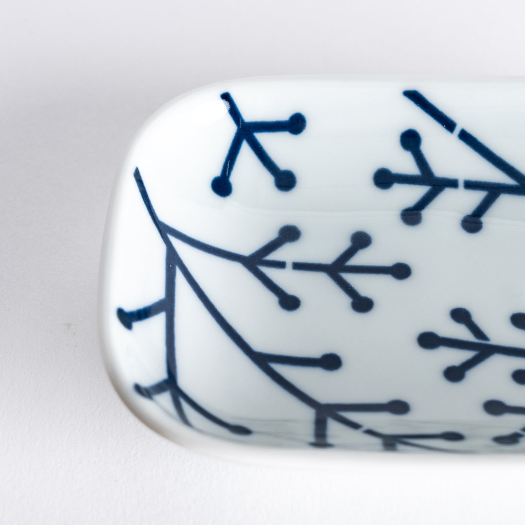 Close-up image highlighting the intricate navy blue pine branch design on the white surface of the dish.