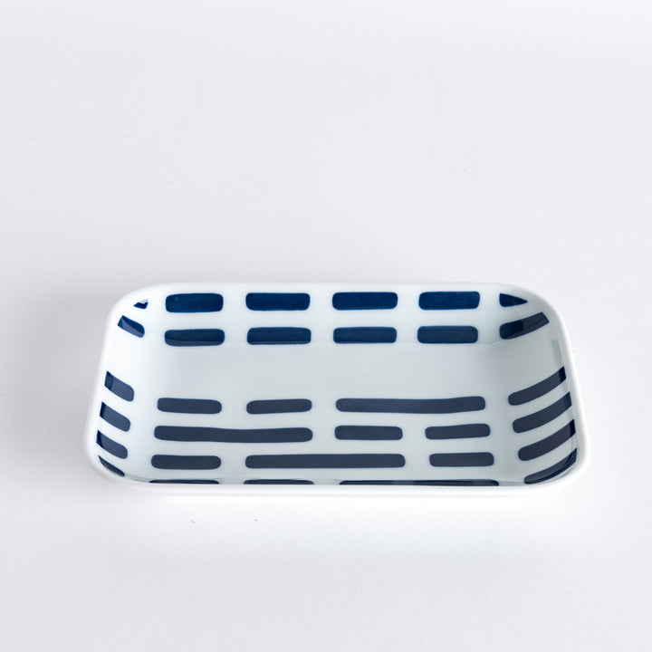 Slightly angled view of a hand holding a rectangular dessert plate with modern blue river-like line patterns.