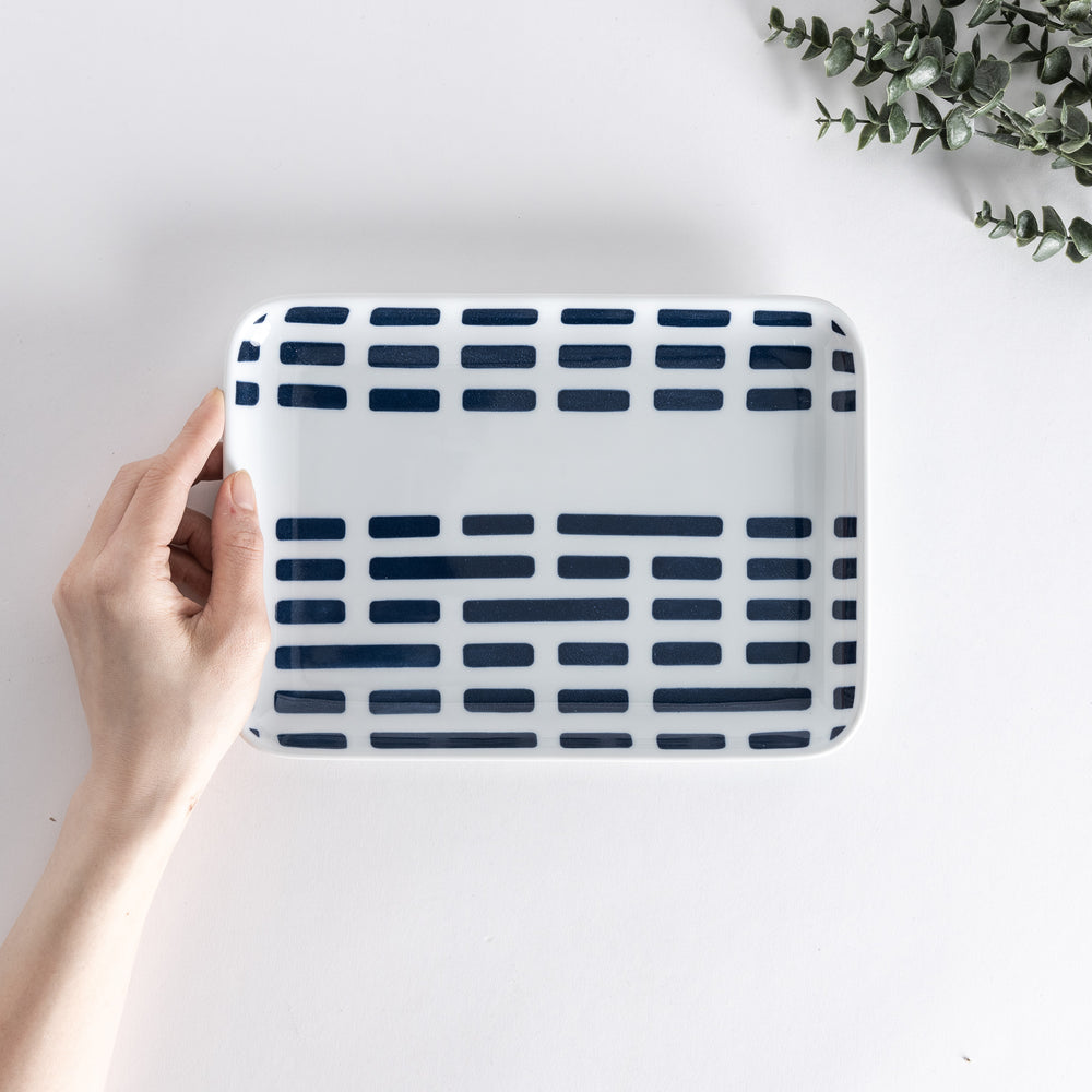 Handheld view from above, showing the Modern Indigo River Dinner Plate with navy blue rectangular patterns on a white background.