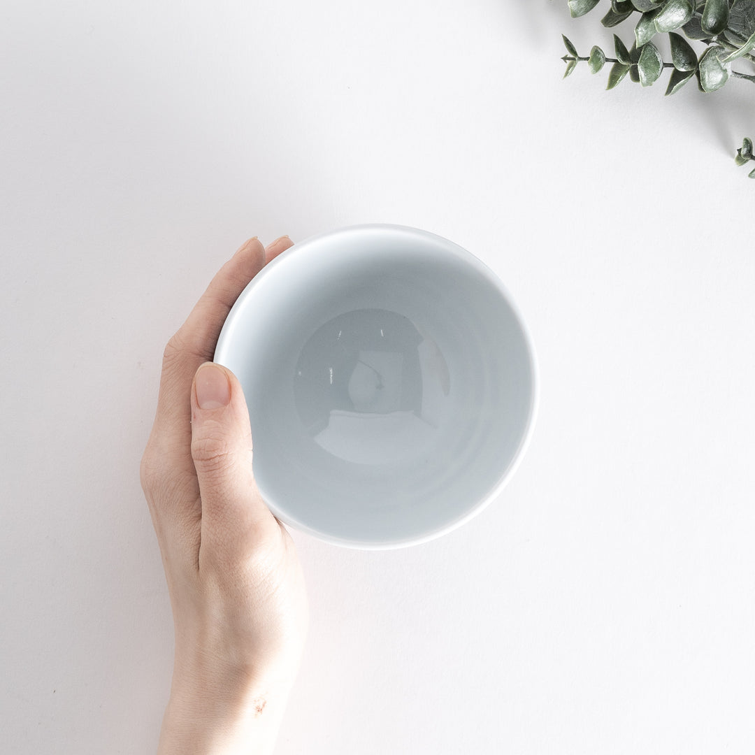 Rice bowl with a horizontal navy blue line pattern, held and photographed from directly above.