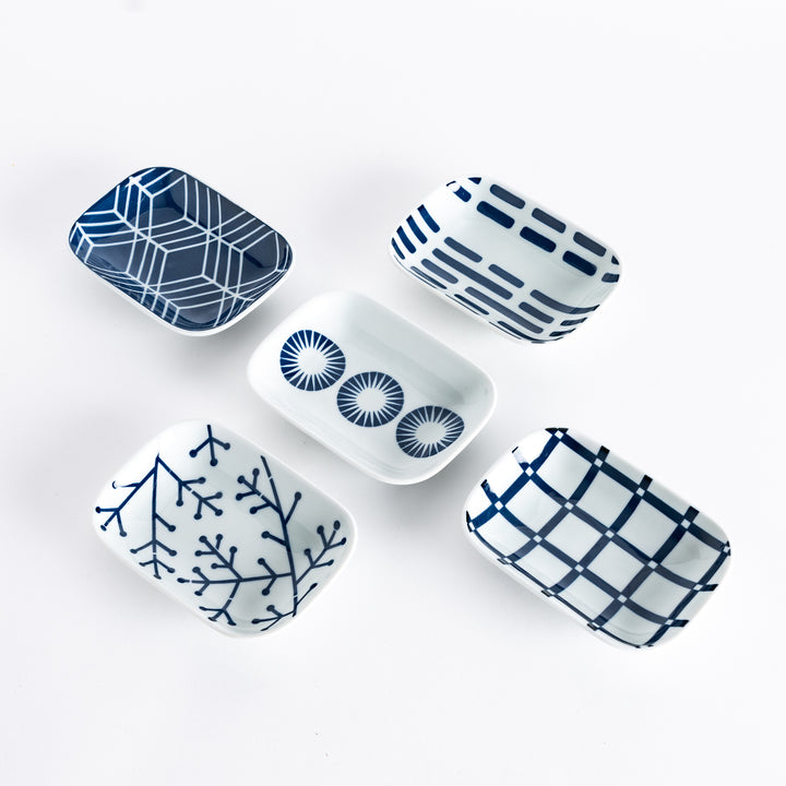 Five different sauce dishes with unique indigo patterns, including geometric shapes, lines, and circular designs, on a white background.