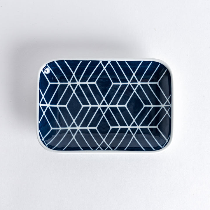 A rectangular dessert plate with a bold, geometric indigo tile pattern, featuring intricate diamond shapes outlined in white on a deep blue background.