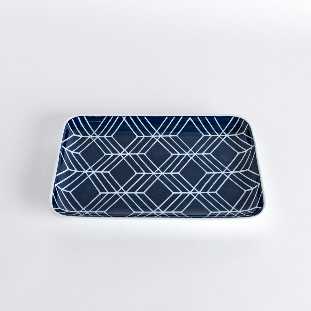 Slightly angled view of the Modern Indigo Tile Dinner Plate with bold white geometric diamond shapes on a navy blue base.